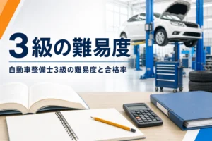 自動車整備士3級の難易度と合格率を紹介する記事のアイキャッチ。教科書と電卓が置かれた机と整備工場